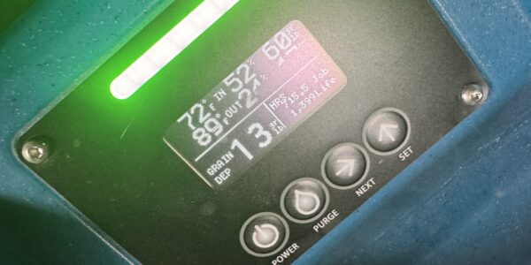 Close-up of an electronic control panel with a digital display showing numbers and settings, surrounded by buttons labeled Power, Purge, Next, and Set—used for monitoring sump pump failure in Toronto—mounted on a blue surface.